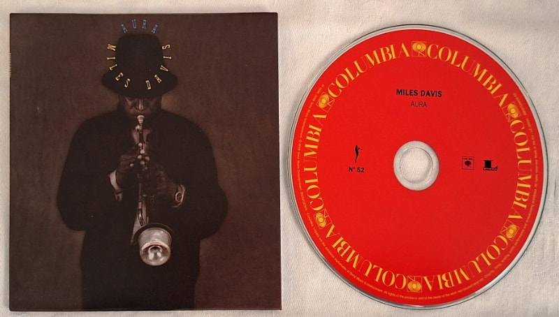 The Complete Columbia Album Collection (CCAC) boxed set offers Aura in a small cardboard sleeve with a red Columbia Records label on the CD.