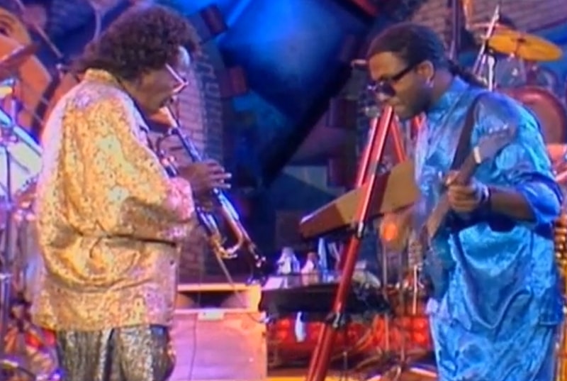 Miles Davis plays trumpet facing the bassist Foley on stage.